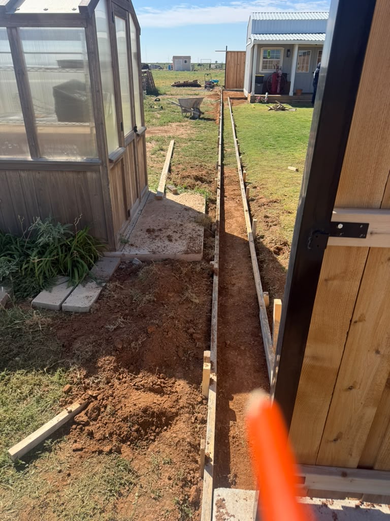 Straight curb forms set beside the lawn before the pour.