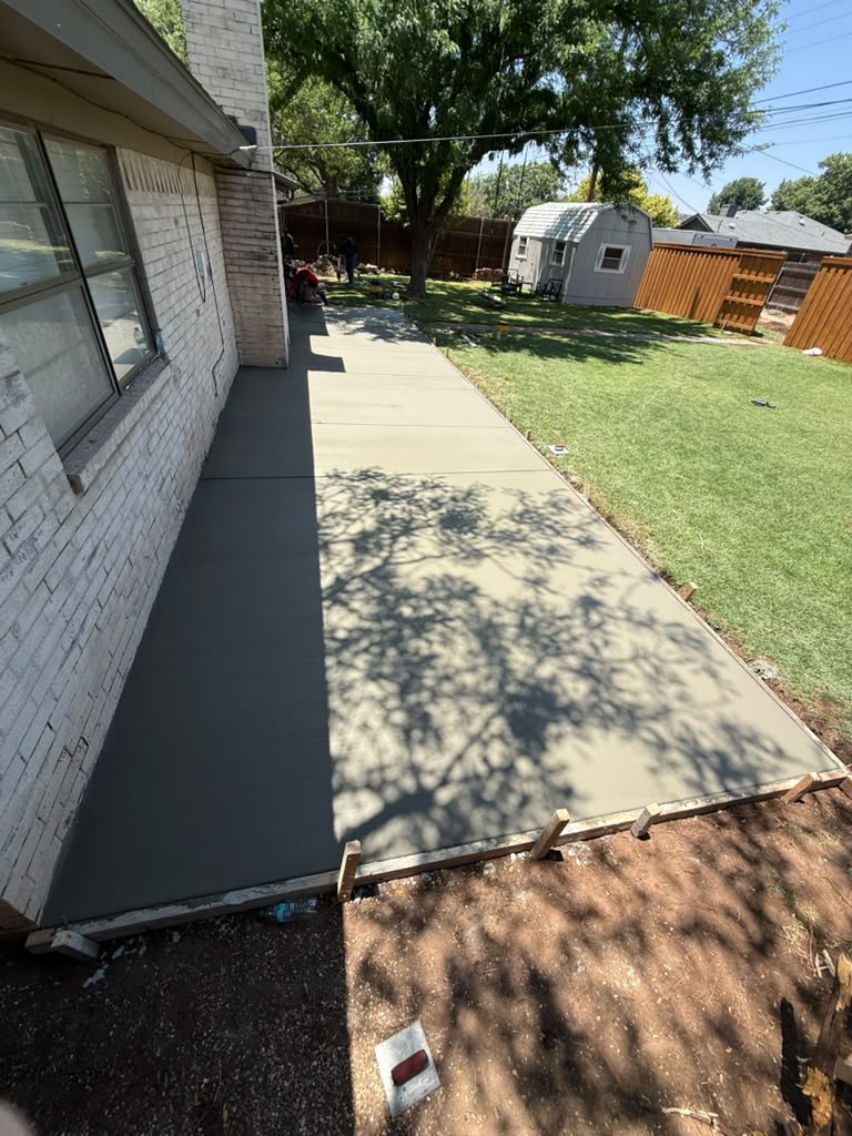 Fresh flatwork pour along the side of the house, forms still on.