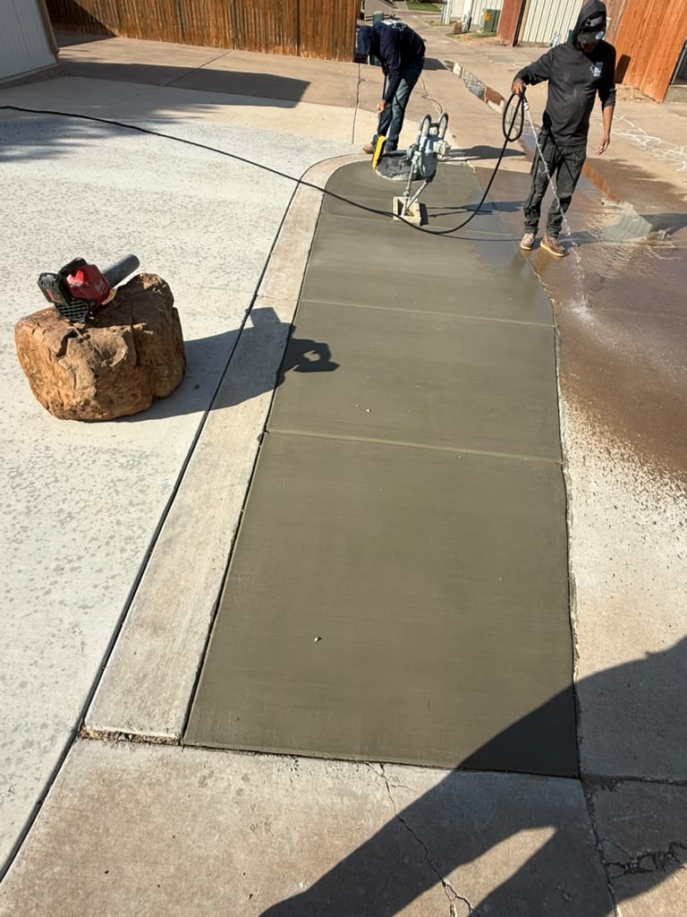 Crew smoothing a curved concrete strip alongside the existing driveway.