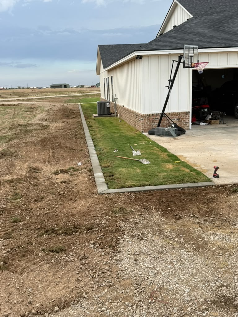 Concrete edging wraps the lawn beside the garage and driveway.